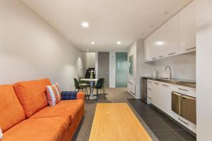 un soggiorno con divano arancione e una cucina di Top of the Lake Apartment a Queenstown Altre 5 foto