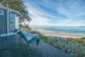 una silla sentada en un porche junto a la playa en The Lookout en Karitane