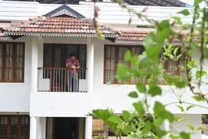 a woman standing on a balcony of a house at Ananda Holiday Home in Ambalavayal