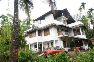 a house with a car parked in front of it at Ananda Holiday Home in Ambalavayal