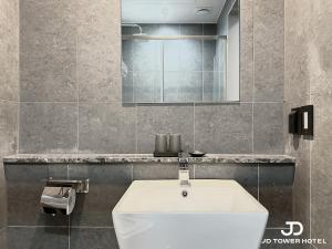 JD Tower Hotel في سول: حمام مع حوض أبيض ومرآة