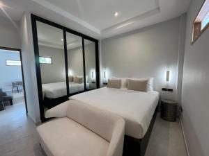 1 dormitorio con cama, sofá y espejo en Moorea Boutique Resort Samui en Koh Samui