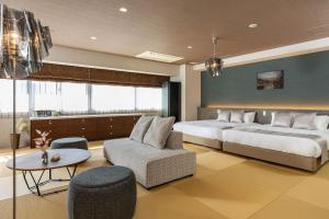 a bedroom with two beds and a couch and a table at JAPAVISTA Xenith Premium in Osaka