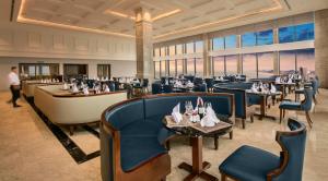 岘港Luxurious Ocean View Suites - My Khe Beach Front - Hinata Apartment的有蓝色椅子、桌子和窗户的餐厅