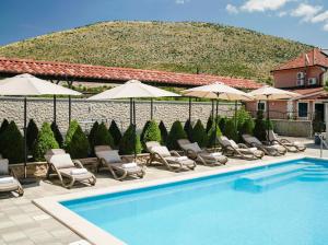 a swimming pool with lounge chairs and umbrellas at Apartments Antonia in Šibenik