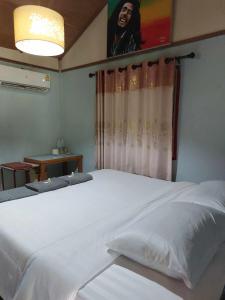 - une chambre avec un grand lit blanc et une fenêtre dans l'établissement Thong Family Homestay Chiangdao, à Chiang Dao