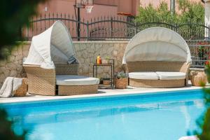 2 sillas de mimbre sentadas junto a una piscina en Apartments Antonia en Šibenik
