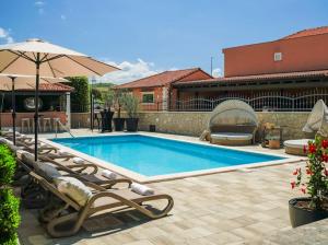 una piscina con tumbonas y sombrilla en Apartments Antonia en Šibenik
