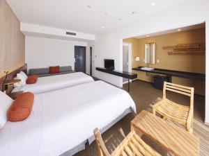 een hotelkamer met 2 bedden en een stoel bij Hotel Rotterdam Huis Ten Bosch in Sasebo