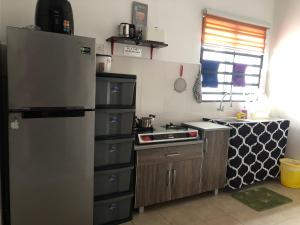 a kitchen with a refrigerator and a stove at Al Ghazali Homestay in Seri Iskandar