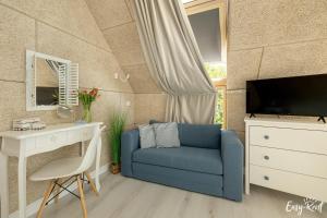 a living room with a blue couch and a desk at Nowoczesny Domek z Jacuzzi 1 in Wrzosowo