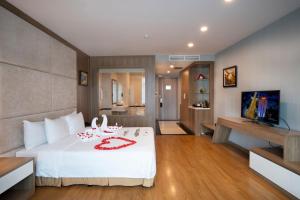 Muong Thanh Grand Hanoi Hotel في هانوي: غرفة نوم بسرير ولحاف ابيض