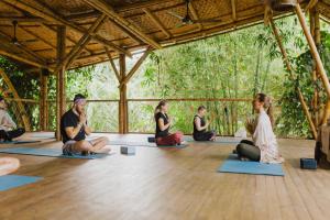 un groupe de personnes assises dans un cours de yoga dans l'établissement YAY Sustainable, à Guachaca
