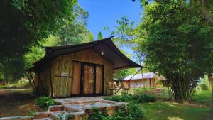 une petite cabane avec un toit noir dans l'établissement "D'BAMBOO KAMP" Desa Wisata Ekang, à Lagoi