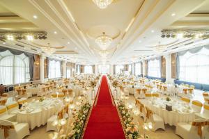 um grande salão de banquetes com mesas e cadeiras brancas em Muong Thanh Grand Hanoi Hotel em Hanói