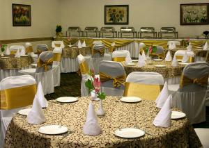 uma sala cheia de mesas com cadeiras brancas e amarelas em ASIA The HERITAGE em Jamu