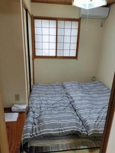 an unmade bed in a room with a window at SUMIDA in Osaka