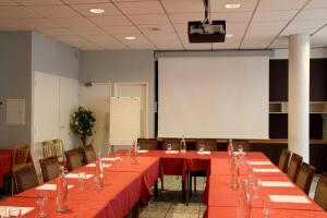 a conference room with red tables and chairs and a screen at Hotel Novel Restaurant La Mamma in Annecy