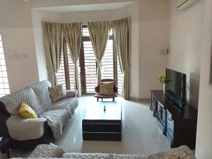 a living room with a couch and a tv at Eden Nomad Living in Batu Ferringhi