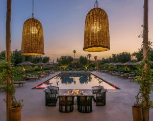una piscina con mesas, sillas y lámparas de araña en The Source Hotel Music & Spa, en Marrakech