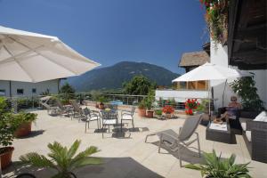 a patio with chairs and umbrellas with a mountain in the background at Garni-Hotel Tritscherhof in Tirolo