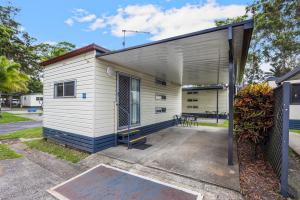 a small white building with a garage at Reflections Coffs Harbour - Holiday Park in Coffs Harbour