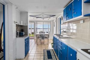 a kitchen with blue cabinets and a dining table at Waterfront Escape Kayaks and Home in Gorokan
