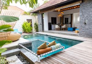 a swimming pool with a chaise lounge next to a house at Lalasa Villas Canggu in Canggu
