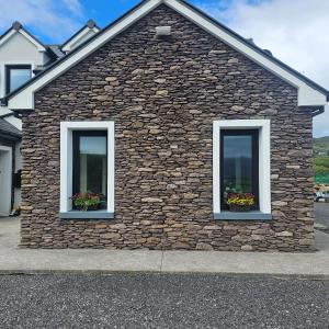 un edificio de piedra con dos ventanas con flores. en The Cé Hideout, en Tralee