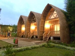 a house made out of straw with a person standing in front at Villa ChavaMinerva Bambu - Lembang in Cikareumbi 2