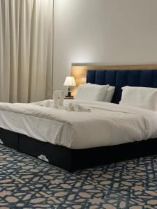 a large bed with white sheets and a blue headboard at شقق ضيف بارك للشقق المخدومة in Ad Dawādimī