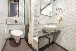 a white bathroom with a toilet and a sink at FabHotel Shubhangan in Mumbai