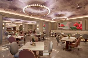 a restaurant with tables and chairs and a chandelier at Mercure Xi'an International Airport in Xianyang
