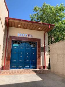 um edifício com uma porta de garagem azul com um sinal de hop em UYUT INN Hotel em Samarcanda