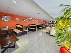 een restaurant met banken, tafels en planten bij ADRAK BOUTIQUE HOTEL in Trivandrum