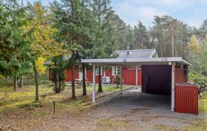a red house with a garage in a forest at Charming Cottage Close To The Beach in Vester Sømarken