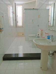 a white bathroom with a sink and a toilet at Casa Turramè in Carini