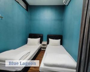 Duas camas num quarto com paredes azuis em Roxy Sematan Townhouse - Blue Lagoon em Sematan
