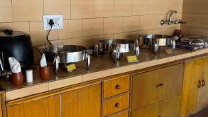una cocina con 3 ollas y sartenes en una encimera en Rock Castle Residency, en Leh