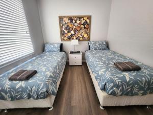 a bedroom with two beds and a table with a lamp at Unit 51 Seafront Estate in Jurien Bay