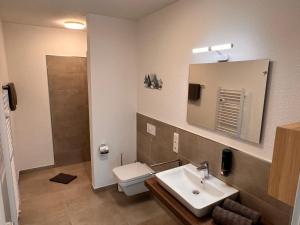 uma casa de banho com um lavatório, um WC e um espelho. em Neues Apartment Nordisch bei Nature by Fewo & Zimmer Bruns em Emden