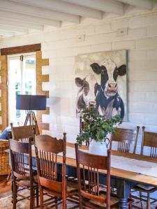 a dining room with a table with a cow painting on the wall at Petana Farm Stay in Morton