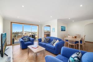 ein Wohnzimmer mit blauen Sofas und einem Tisch in der Unterkunft Scenic Beachside Apartment, near Bar & Restaurant in Terrigal