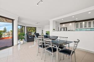 a kitchen and living room with a glass table and chairs at Spacious Modern Apartment with Breathtaking Views in Terrigal