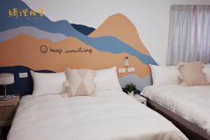 twee bedden in een kamer met een bergmuurschildering aan de muur bij 寮寓x綺澄 包棟宅 in Xiaoliuqiu