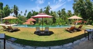 einen Pool mit Stühlen und Sonnenschirmen davor in der Unterkunft S`ekar Pinang Langkawi in Pantai Cenang