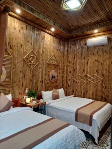 1 dormitorio con 2 camas y pared de madera en Tam Coc Village Bungalow, en Ninh Binh