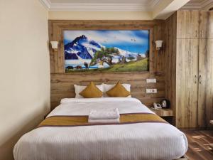 een slaapkamer met een groot bed met een schilderij aan de muur bij Prem Durbar Hotel in Changunarayan
