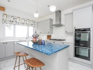 a kitchen with white cabinets and a blue counter top at Pine Lodge in Colwyn Bay