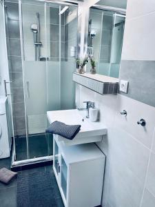 a white bathroom with a sink and a shower at Apartmány na Zahradní in Břeclav